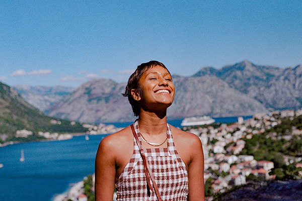 Woman smiling with a coastal, mountainous city in the background 
