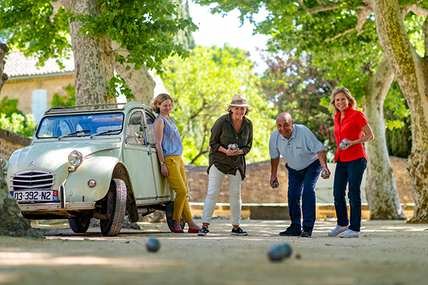 People playing bowls next to an old European car