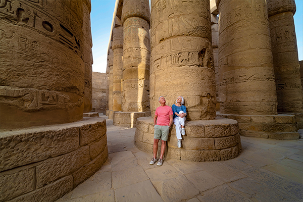 Two people looking up at tall columns covered in hieroglyphics