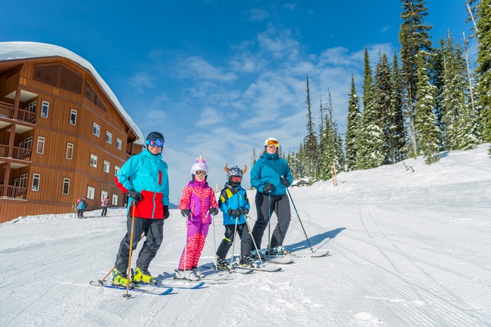 A family of four about to hit the slopes on skis at Big White Ski Resort