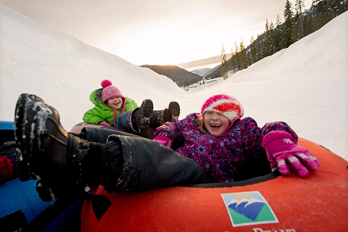A couple of girls laughing as they tube through Sun Peaks resort