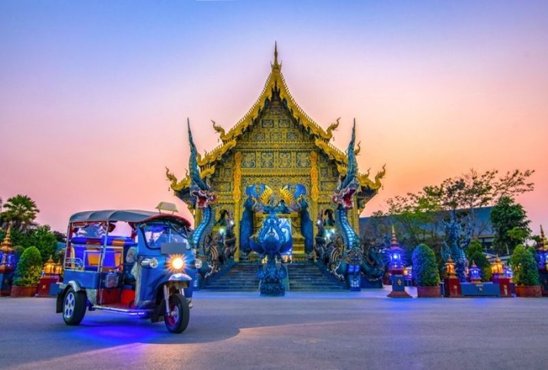 the front view of the blue temple before night with a motorcycle taxi parked in front of it
