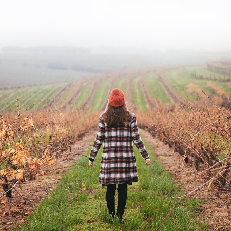 Lady in a fall outfit standing in the middle of a field