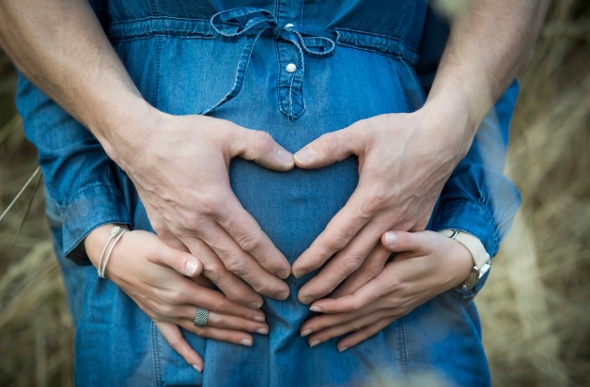 Maternity photo shoot of a bump with hands in a heart form