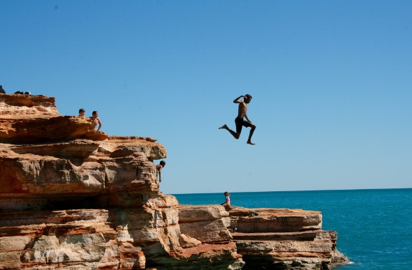 Friends cliff diving into the ocean