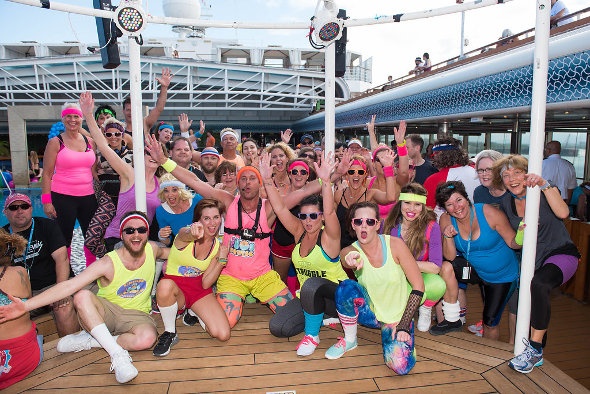  a group of people in their colorful 80s workout outfits on a cruise ship