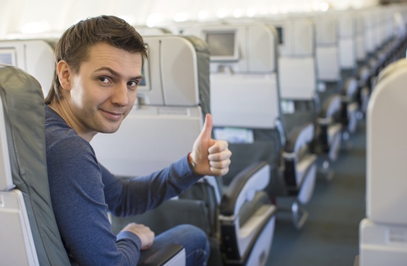  a guy in blue sweaters smiling while giving a thumbs up for good service on the plane