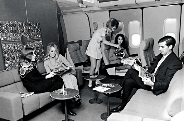 Black and white image of passengers lounging inside a plane in the 90's