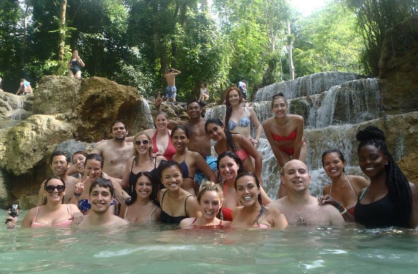 Group of tourists posing for a photo while relaxing at the end of a waterfall
