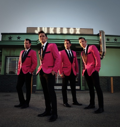 Four men dressed in pink suits in front of an establishment