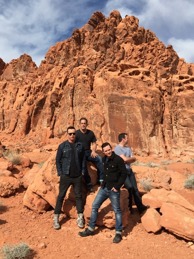 Four men posing on a rock in Nevada desert