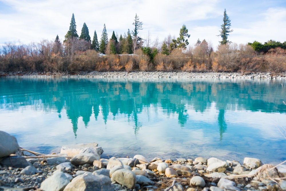  the crystal blue waters of lake tekapo surrounded by white and beige stones