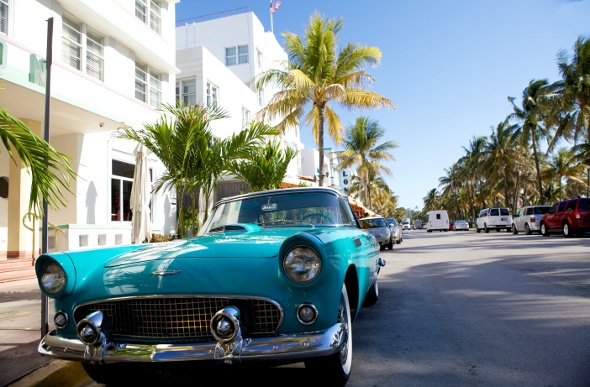  a teal car driving across miami streets during daylight