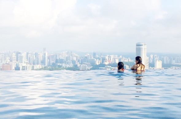  Two people swimming in an infinity pool looking out to the city skyline 