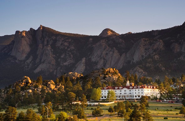  Stanley hotel with the view of trees and the mountain behind it
