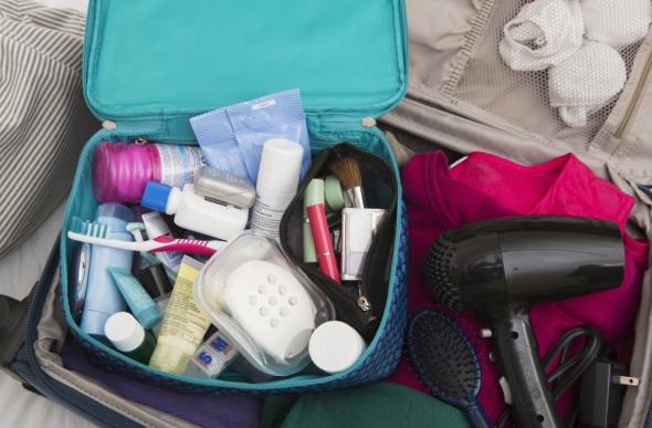  a suitcase with a blower and a blue bag full of toiletries and make up