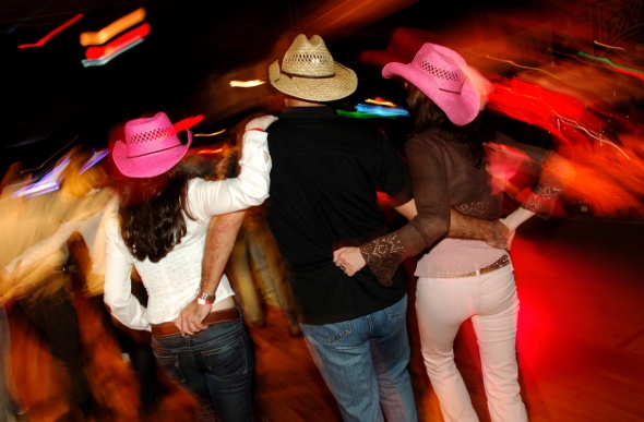 Three people celebrating and drinking in cowboy hats  