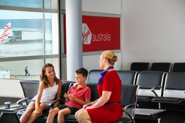 Young Virgin Australia passengers with a flight attendant in the airport lobby