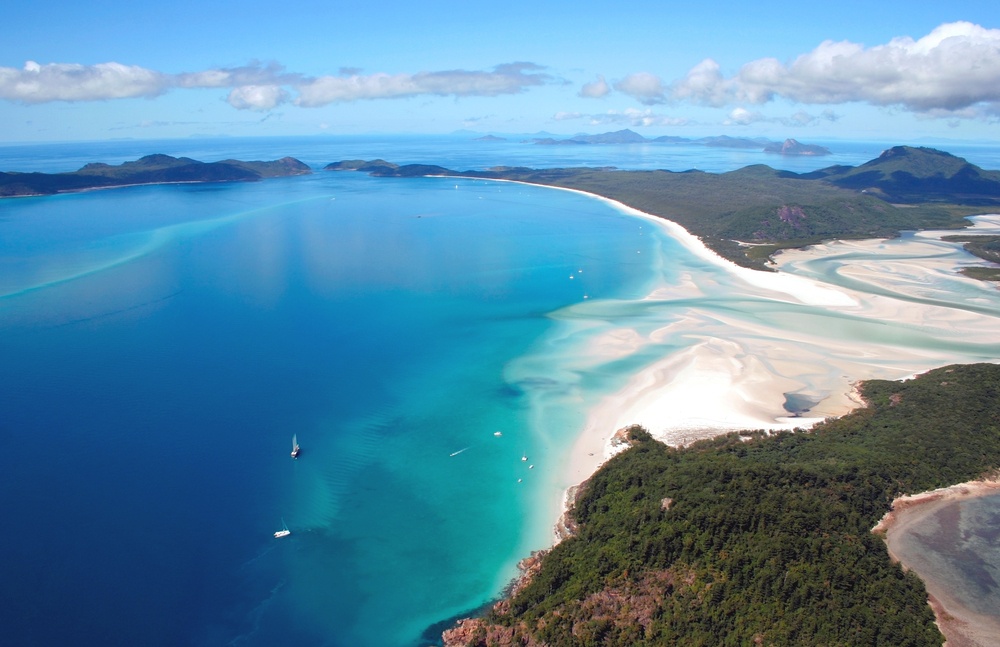  a majestic aerial view of the islands. white san, and cerulean waters of the whitehaven beach in queensland
