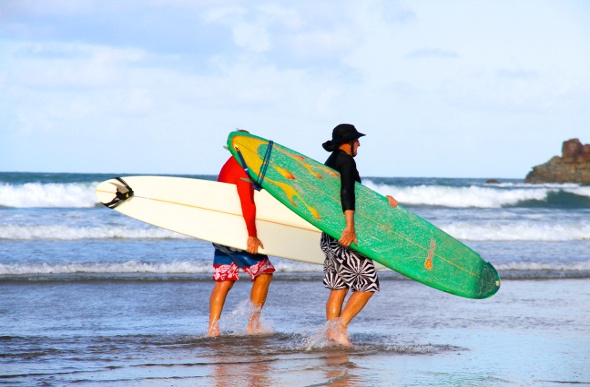 Two men walking on the beach with their surfboards