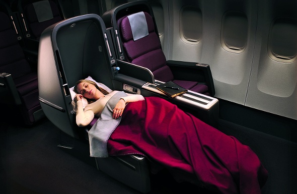 Lady comfortably sleeping in a spacious business seat on Qantas Airline