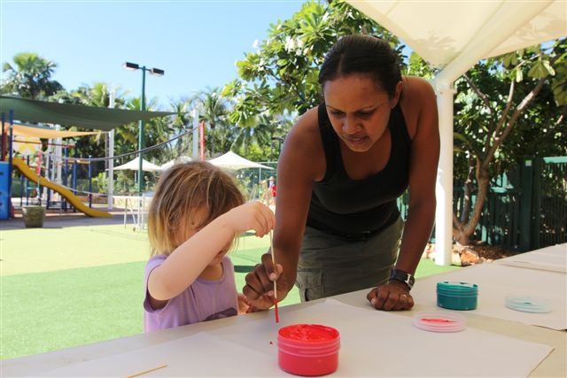  a woman assisting a little girl with painting