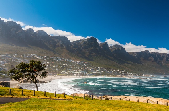  a serene view of the blue waters, green meadows, and mountainous background of the Camps Bay