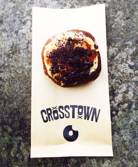  a cookie sprinkled doughnut on top of the crosstown paper bag