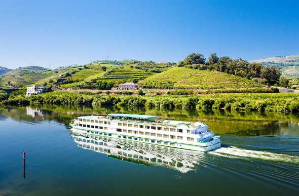  River cruise ship goes past green hills of Douro Valley in Portugal 