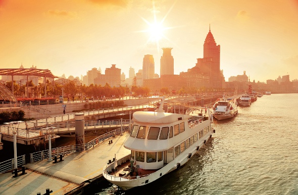  A boat on Huangpu River in shanghai at sunset with city buildings in the background 
