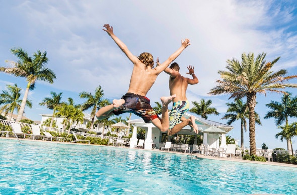 Two young boys jumping into a swimming pool