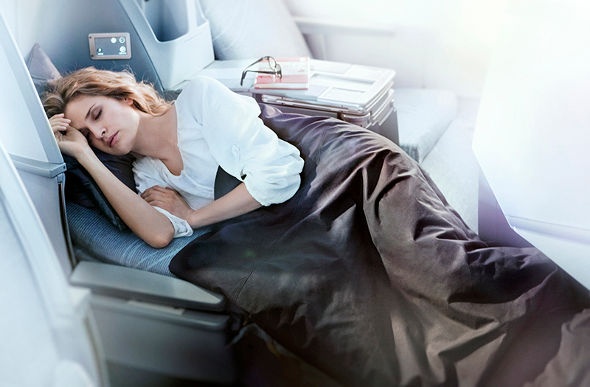  a redhead girl sleeping comfortably in Finnair's business class with a book and glasses on her side