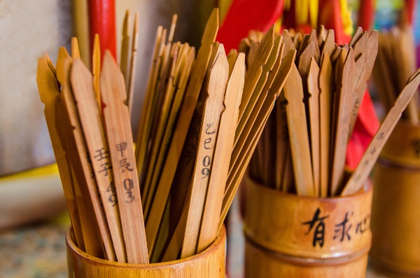  two piles of Kau Chim fortune sticks in separate bamboo holders