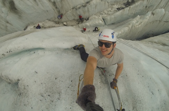  a man in gray shirt taking a selfie as he climbs the mountain