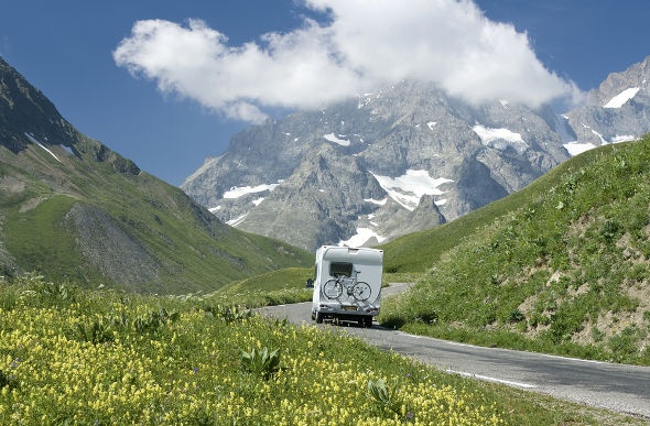 a camper van with a bike on its back driving through the road heading to the french alps