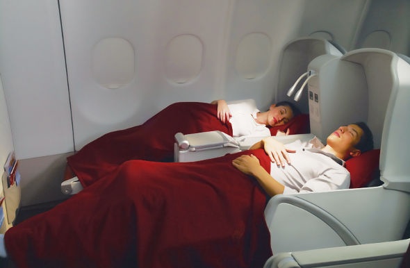 Couple sleeping comfortably in the spacious reclining seats in Garuda Indonesia's executive class