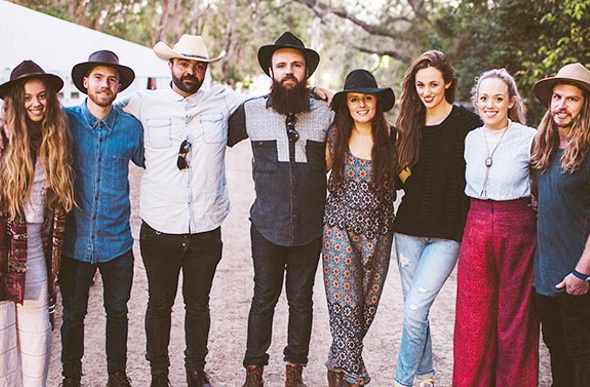 Indie group wearing cowboy hats and hipster clothing pose for a shot