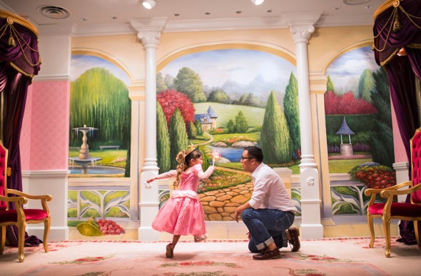 Child dressed as a princess playing with his father