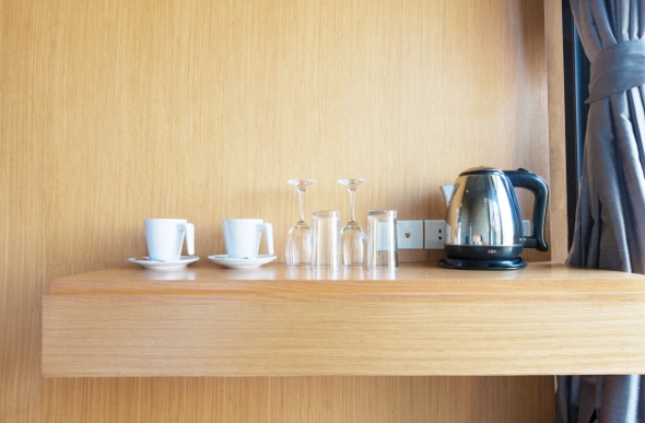  a wooden coffee corner in the hotel with two white mugs, two champagne glasses and an electric kettle