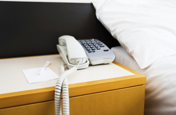  a tiled bedside table with a white telephone, pen, and notepad