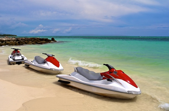  three white and red jet skis lined on the beach shore