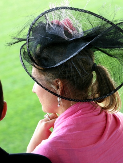  woman in pink dress and black see through hat with feathers