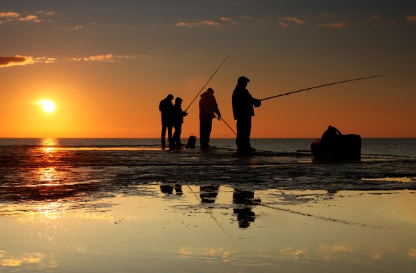 four men beach fishing at sunset