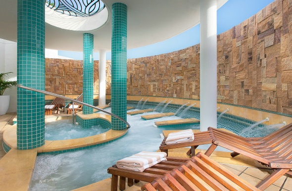 A gorgeous spa with flowing water and wooden lounge chairs