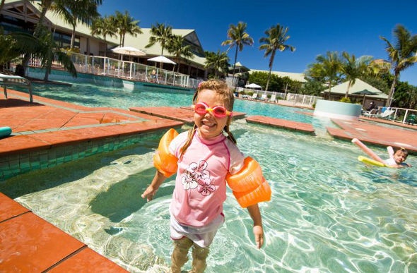  a blonde littel girl in pink shirt and orange floaters enjoying the pool in the Novotel twin waters resort