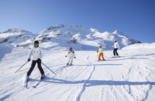 a family of four enjoying a nice skii togetheron a snowy mountain