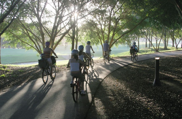  a group of people riding a bike in a narrow path covered with trees in Palmer Coolum Resort