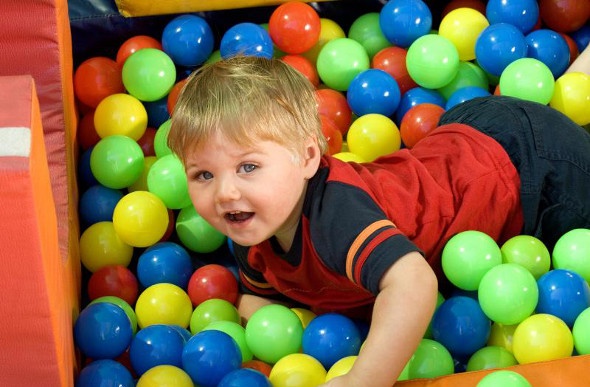  a little blonde boy swimming through small plastic ball toys