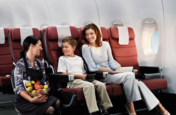  A Qantas economy flight attendant offering fruits to the mother and her son