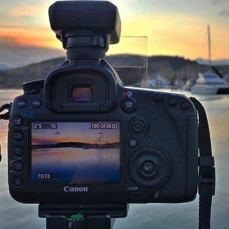 Photo of a digital camera taking a picture of a sunset scenery 